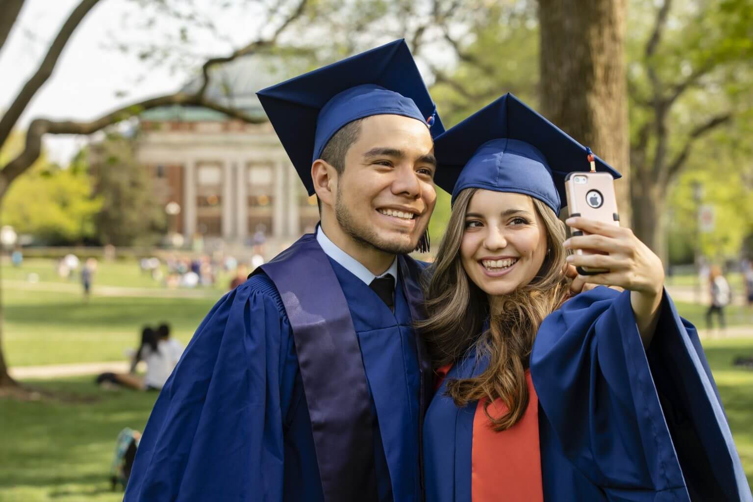 Two students taking a graduation selfie in their caps and gowns